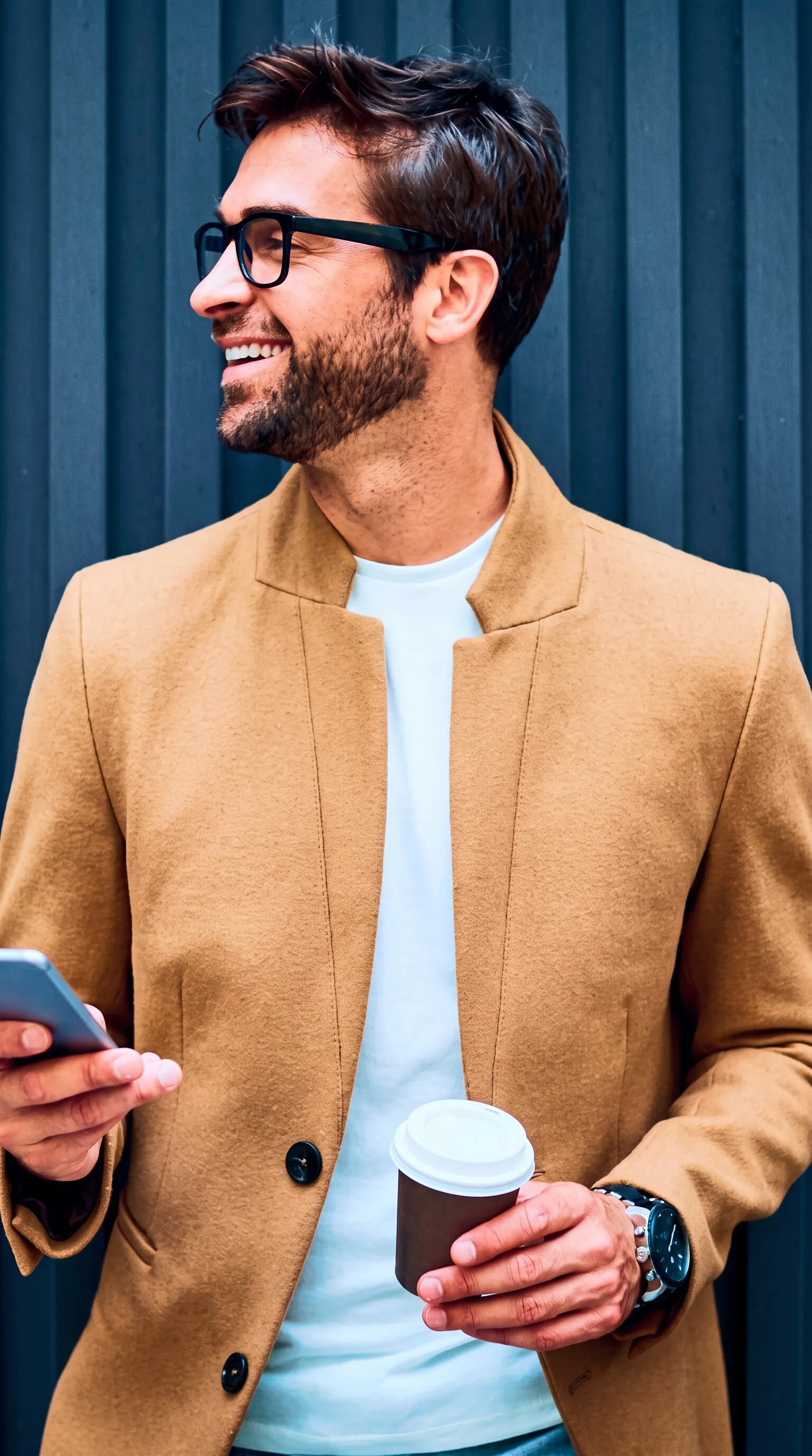 Homem sorrindo com óculos, celular e copo de café