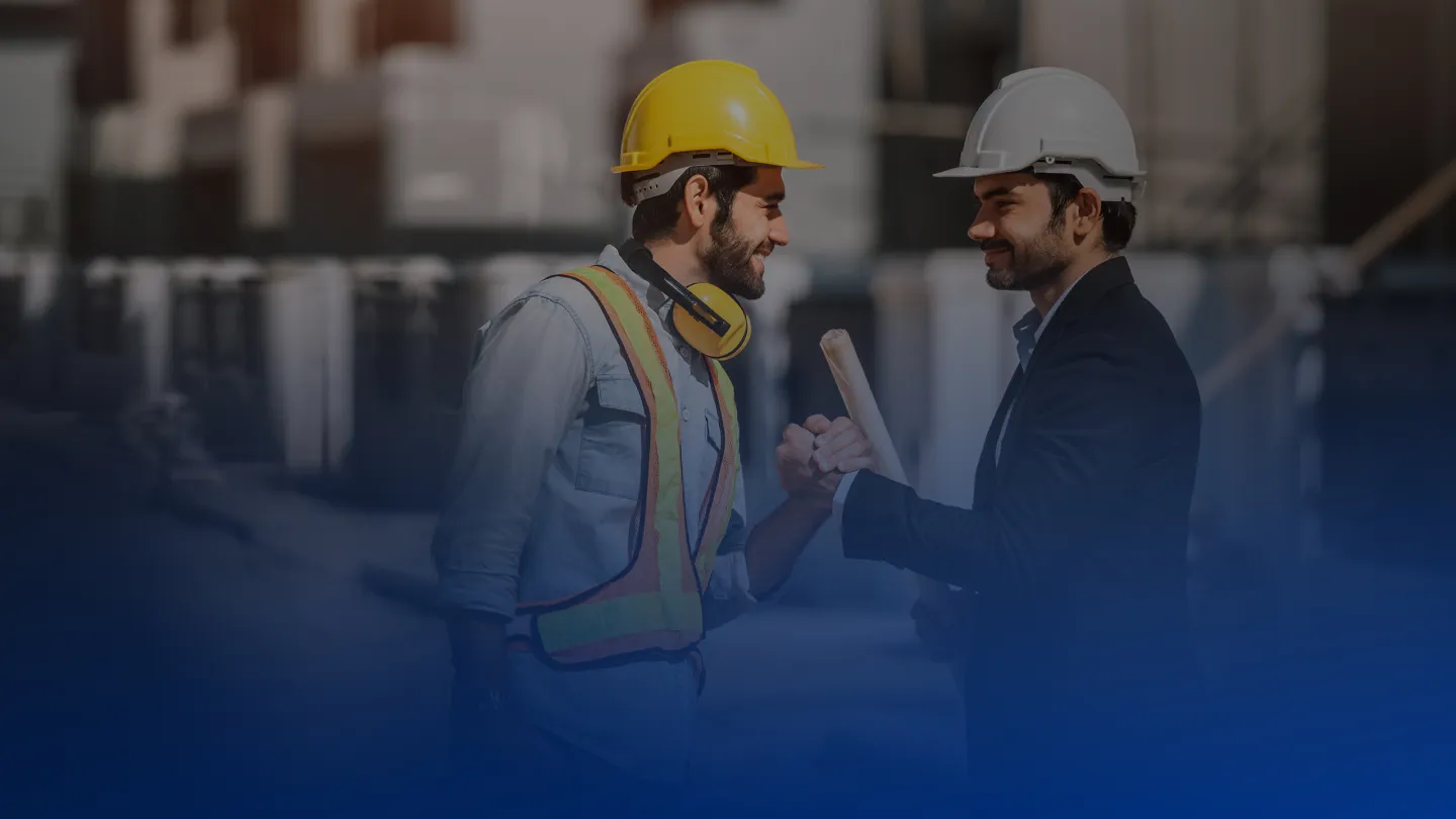 Dois profissionais da construção civil conversam em um canteiro de obras
