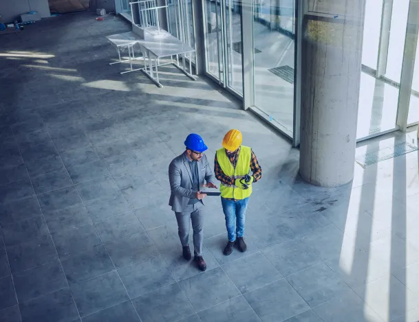 Engenheiro e profissional da construção analisando uma obra